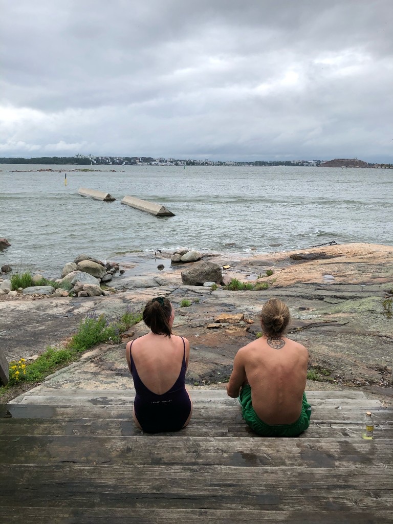 Sea swimmers sitting on wooden steps facing the Baltic